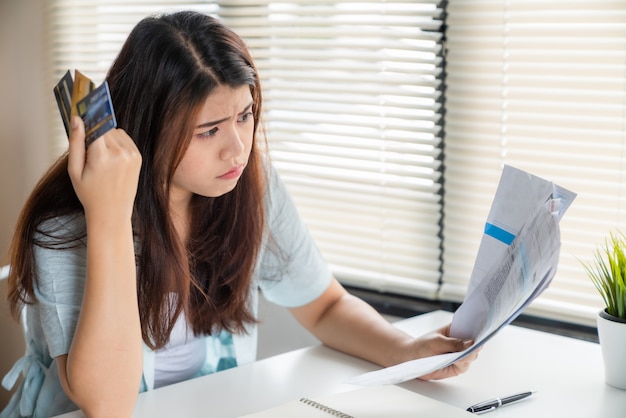 Stressed young asian woman holding bills in her hand