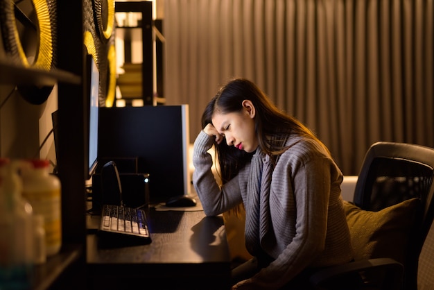 Stressed young Asian woman looking tired while working from home