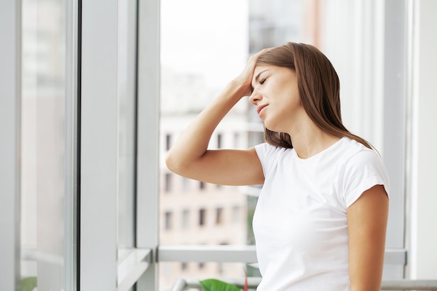 Stressed young office worker holding head because of pain in office