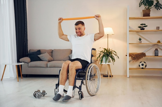 Stretching the hands Disabled man in wheelchair is at home