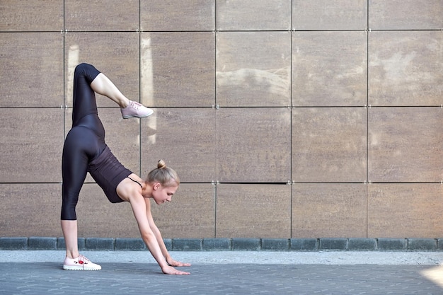 Stretching woman fitness or gymnast or dancer doing exercises on brown wall city urban background