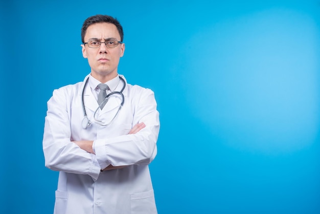 Strict doctor in glasses against blue backdrop