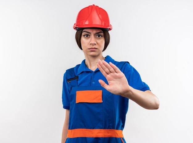 Strict looking at camera young builder woman in uniform showing stop gesture 