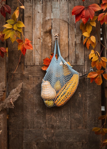 String shopping bag with autumn harvest hanging on old rustic wooden door