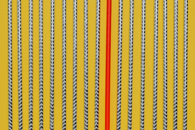 Striped cocktail tubes with a red tube in the middle on a yellow surface