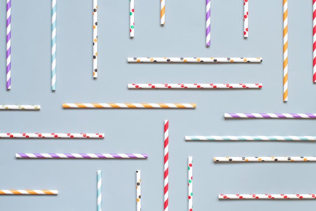 Striped and dotted paper drinking straws on grey background top view. Eco friendly and biodegradable