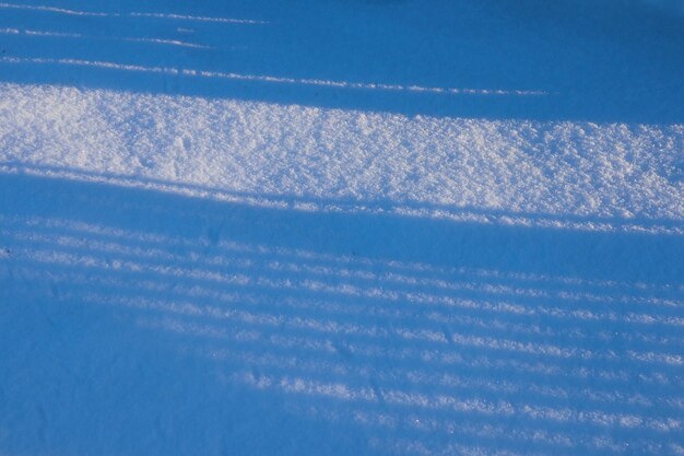 Stripes of shadows on a snowy field on a sunny winter day