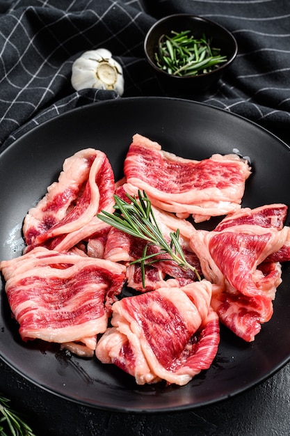 Strips of marbled beef, quick steak. Black background. Top view.