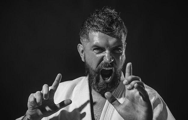 Strong angry bearded man dressed in kimono portrait screaming boxer of self confident brutal man