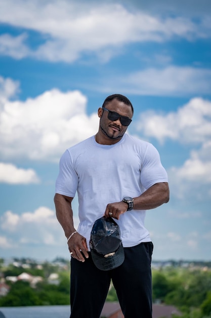 Strong big man in sunglasses outdoor Handsome athletic man in white shirt standing outdoor