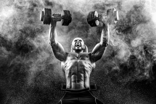 Strong bodybuilder posing and holding dumbbells