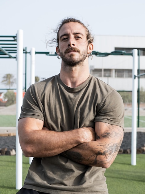 Strong caucasian man with tattoos portrait outdoor in the calisthenics park