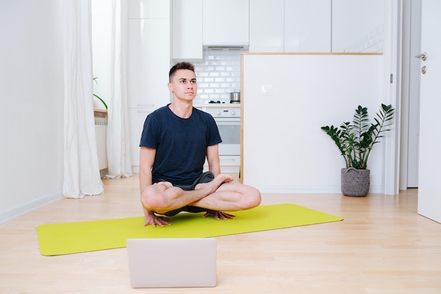 Strong confident man lifting body with his hands practicing yoga at home kitchen