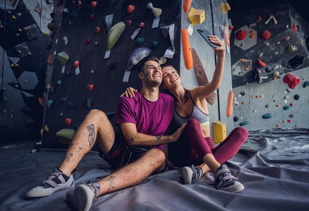 A strong couple of climbers against an artificial wall with colorful grips and ropes