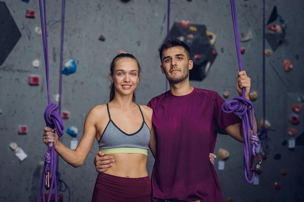 A strong couple of climbers against an artificial wall with colorful grips and ropes