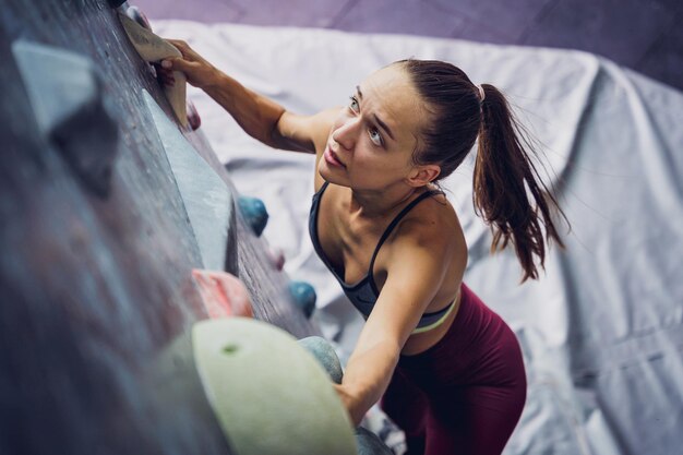 Photo a strong female climber climbs an artificial wall with colorful grips and ropes