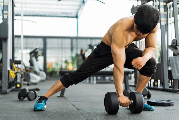 strong fitness man posing muscular body and doing exercises for bodybuilder in the gym