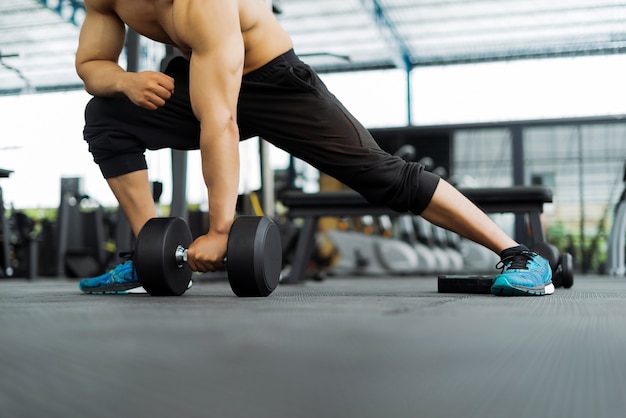 strong fitness man posing muscular body and doing exercises for bodybuilder in the gym