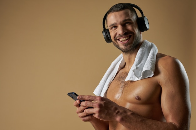 Strong funny athlete with headphones posing at the camera in studio