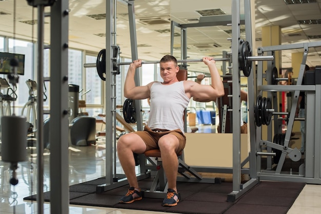 Strong guy with barbell Sportsman concentrated on the sport Young man is pushing barbell