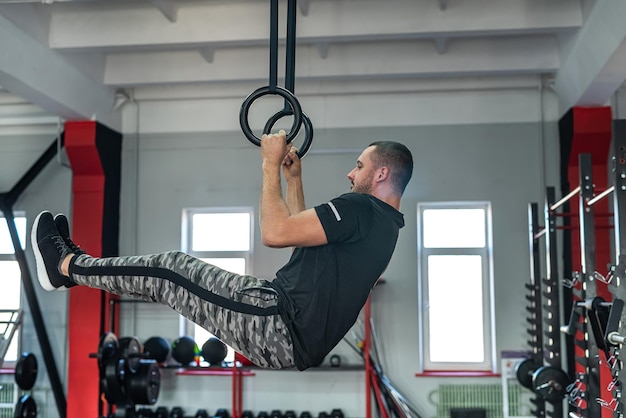 Strong handsome man trainer in sporty fitted clothes trains his clients to improve health