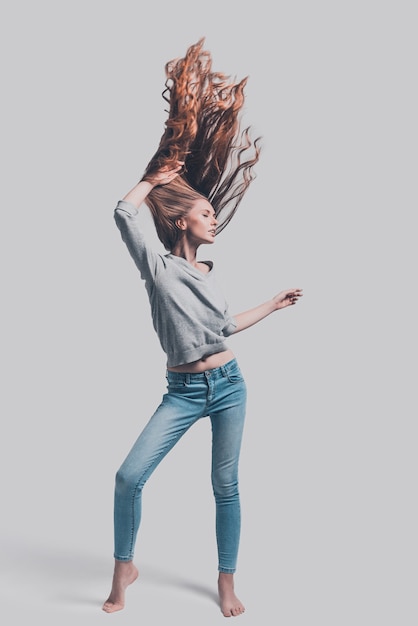 Strong and healthy hair. Full length studio shot of attractive young woman with tousled hair posing 