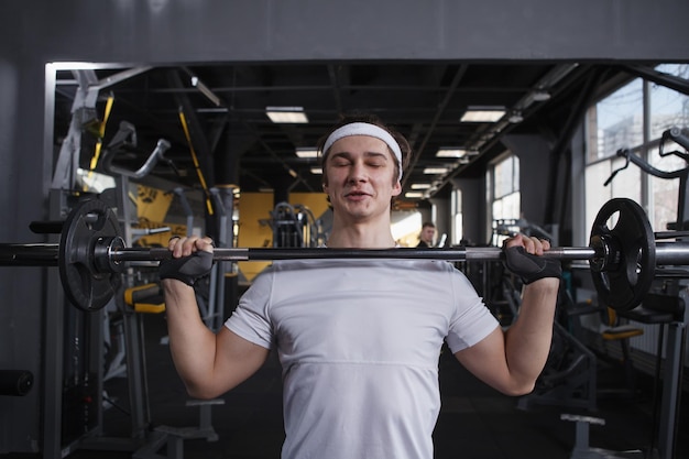 Strong healthy young man doing push press exercise with barbell