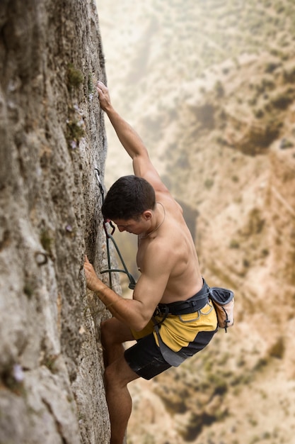 Strong man climbing on a mountain with safety equipment