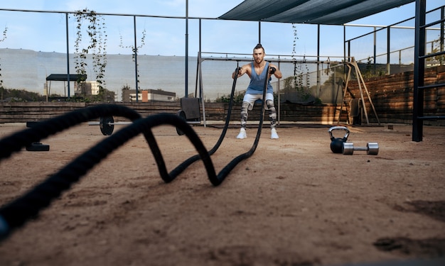 Strong man doing exercise with ropes