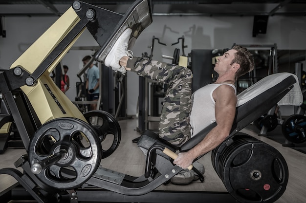 Strong man exercising on machine in gym