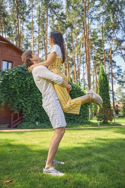 strong man holding beautiful woman on hands in the outdoors