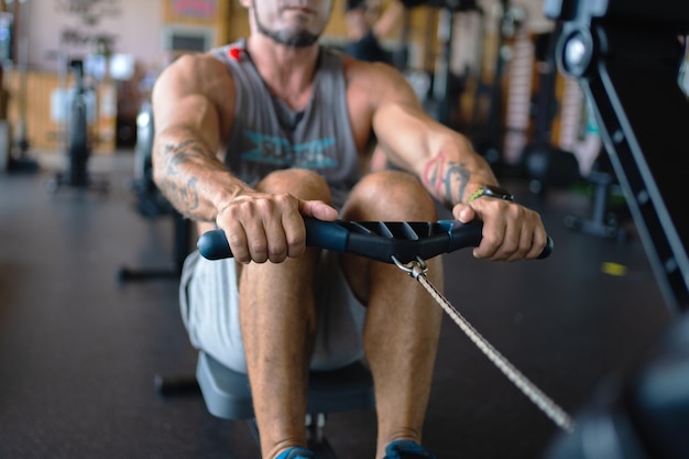 Strong man rowing using a machine in a gym