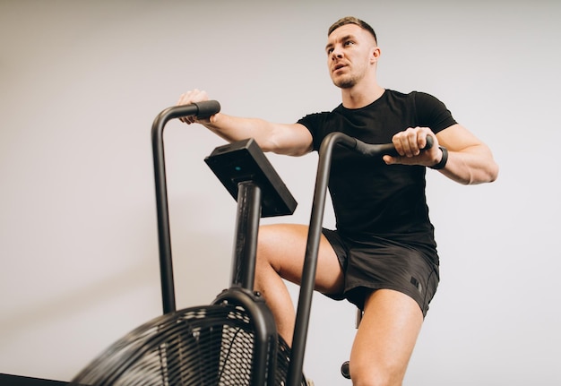 Strong man using air bike for cardio workout at cross training gym