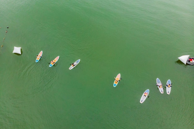 Strong men floating on a SUP boards in a beautiful bay on a sunny day Aerial view of the men crosses the bay using the paddleboard Water sports competitions