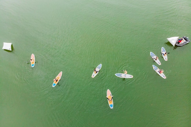 Strong men floating on a SUP boards in a beautiful bay on a sunny day Aerial view of the men crosses the bay using the paddleboard Water sports competitions