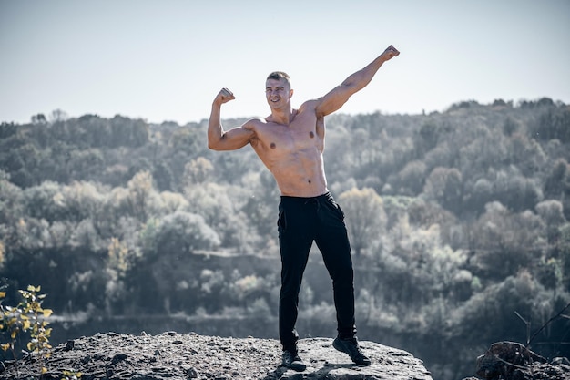 Strong muscular man standing outdoor on landscapes Athletic sporty bodybuilder posing outdoor