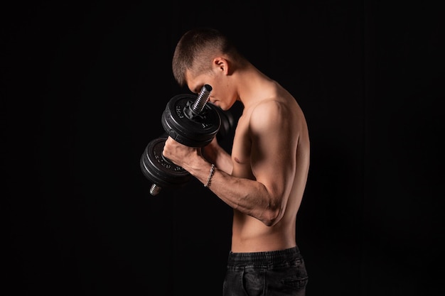 Strong sexy man with dumbbells on a black background