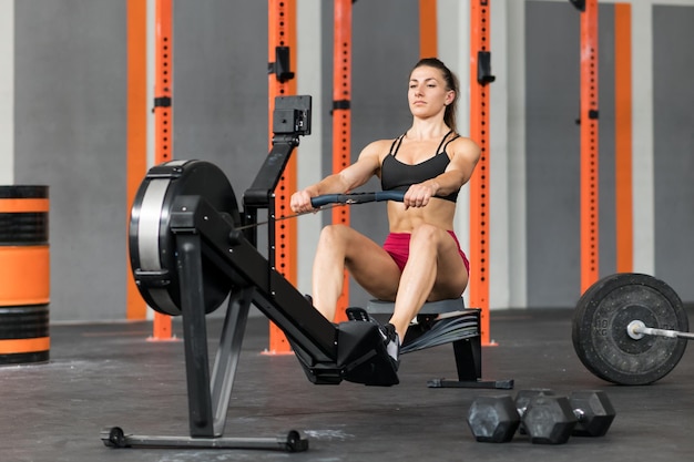 Strong sportswoman exercising on rowing machine