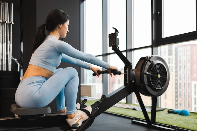 Strong woman is engaged on rowing machine