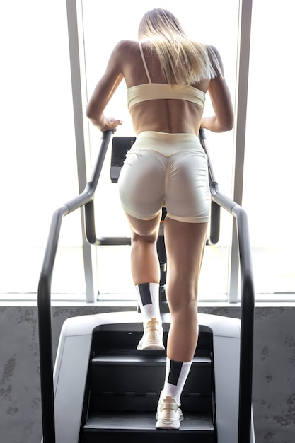 Strong woman warm up training running on a treadmill climber stairs machine