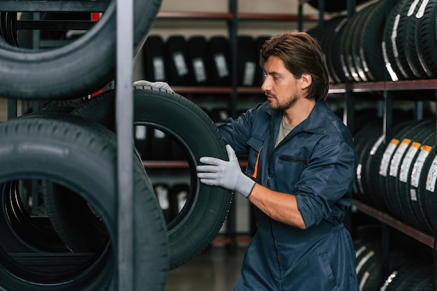 Strong worker is with tire Man is in the tire fitting car service