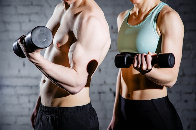 Strong young couple working out with dumbbells. 