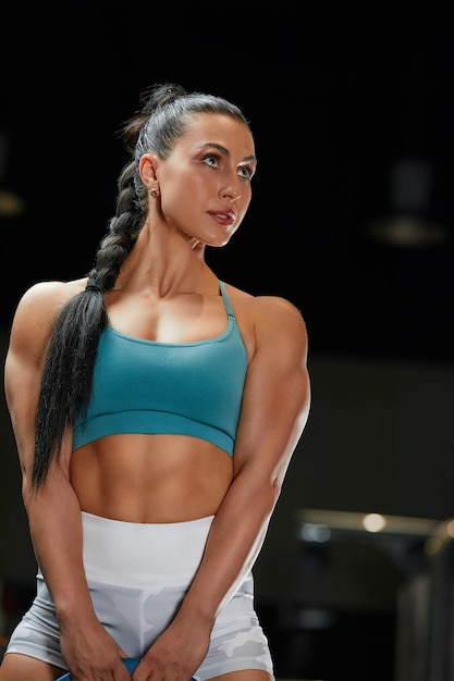 Strongwilled young woman fitness coach engaged with a barbell in the simulator in the gym Concept of strong muscles and taut figure