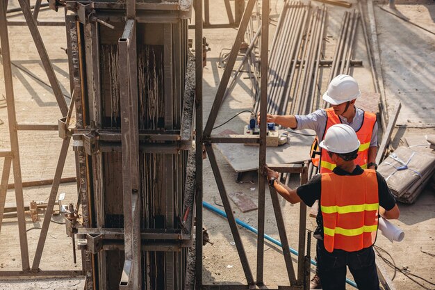 Structural engineer and foreman worker with blueprints discuss plan inspecting for the building