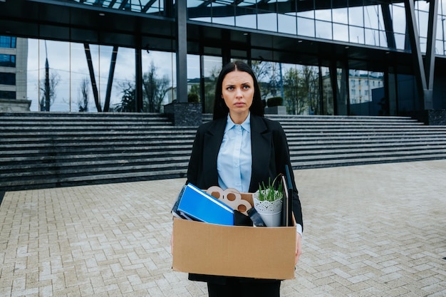 The Struggle of Finding Work After Job Loss An upset woman holds a cardboard box facing the uncertainty of job loss and dismissal