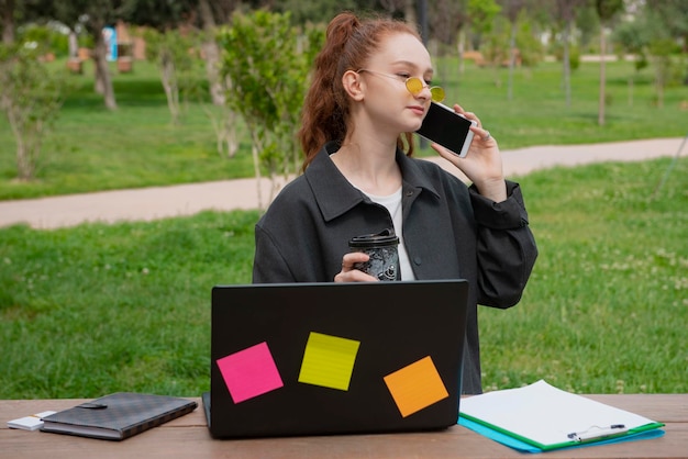 Student freelancer sitting at table looking down holding coffee