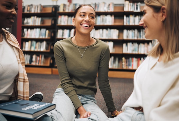 Student friends and book discussion in library with smile for education learning or knowledge at university Group of happy women enjoy conversation book club or social study for research project