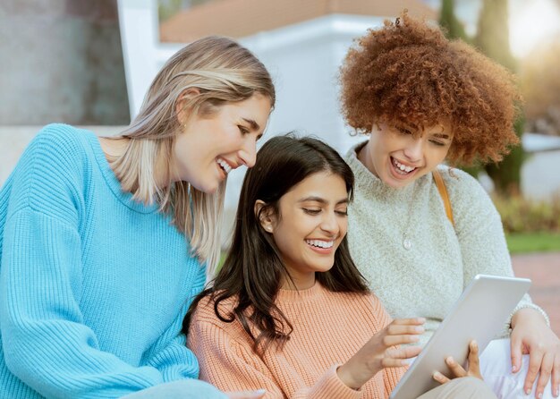 Student friends and tablet laughing for meme social media or streaming online entertainment at campus Happy women sharing laugh for funny joke chat or post on touchscreen together at university