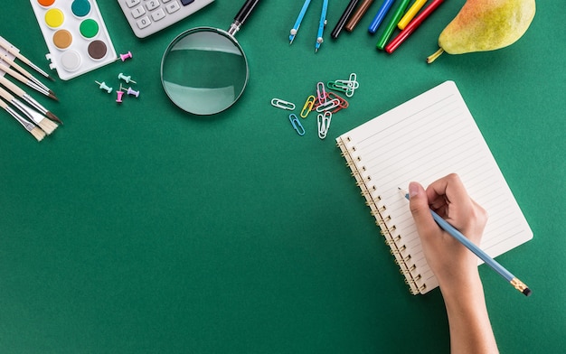 Student of the girl hand from a pencil with notebook and school supplies.