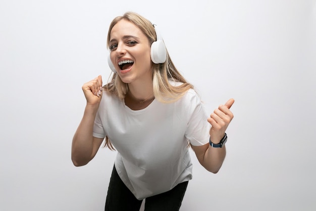 Student girl listening to music with wireless headphones in a studio with white walls